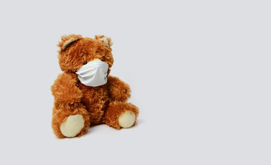 Brown teddy bear wearing a health mask on a white background