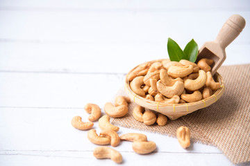 Roasted salted raw cashew nuts with Fresh cashew in spoon and  basket isolated on white wooden...