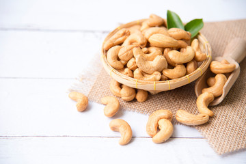 Roasted salted raw cashew nuts with Fresh cashew in spoon and  basket isolated on white wooden background.