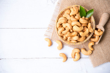 Roasted salted raw cashew nuts with Fresh cashew in spoon and  basket isolated on white wooden background.