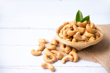 Roasted salted raw cashew nuts with Fresh cashew in spoon and  basket isolated on white wooden background.