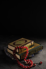 Faith in Islam, Holy book Islamic scripture al-Quran and rosary beads on dark background. Islamic holiday celebration Eid Mubarak or Ramadan Kareem concept.