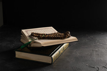 Faith in Islam, Holy book Islamic scripture al-Quran and rosary beads on dark background. Islamic holiday celebration Eid Mubarak or Ramadan Kareem concept.