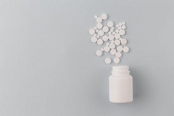 Bottle with white pills scattered on a blue background with soft focus and close-up. Space for text.