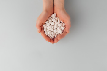 Round white pills on the palm of a female top view, overdose of pills. Copy space. Pharmacy and medical concept