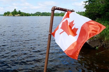 Fototapeta na wymiar Canadian Flag attached to a pole on a dock lakeside at Pelican Pouch Lake, Ontario, Canada