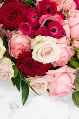 Romantic red, pink and cream roses in a bridal bouquet on marble background