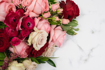 Romantic red, pink and cream roses in a bridal bouquet on marble background