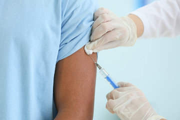 Doctor vaccinating teenage boy in clinic, closeup