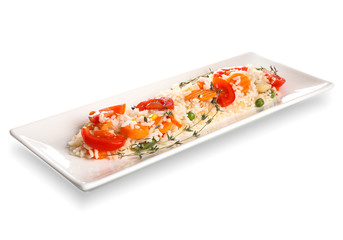 Plate with boiled rice and vegetables on white background
