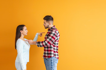 Quarreling young couple on color background