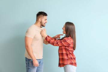 Quarreling young couple on color background