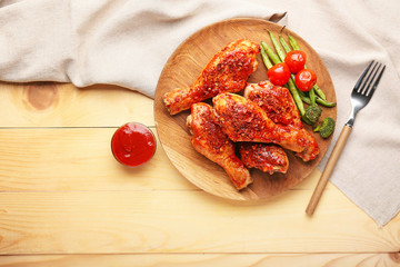 Cooked chicken drumsticks with vegetables and sauce on table