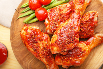 Cooked chicken drumsticks with vegetables on plate, closeup