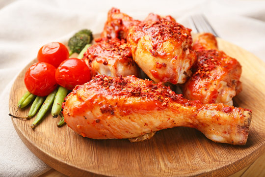 Cooked chicken drumsticks with vegetables on plate, closeup