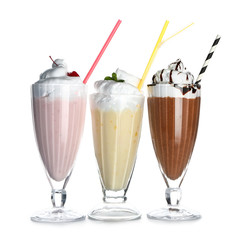 Glasses of tasty milkshakes on white background