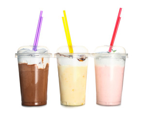 Cups of tasty milkshakes on white background