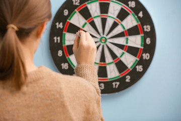 Young woman playing darts indoors