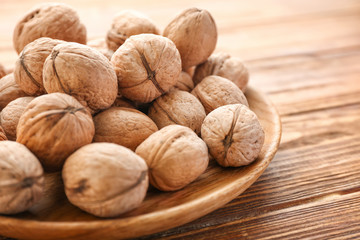 Plate with tasty walnuts on table, closeup