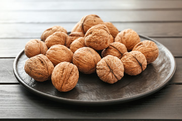 Plate with tasty walnuts on table