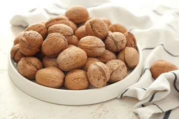 Plate with tasty walnuts on table