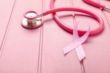 Pink ribbon with stethoscope on white wooden background. Breast cancer awareness concept