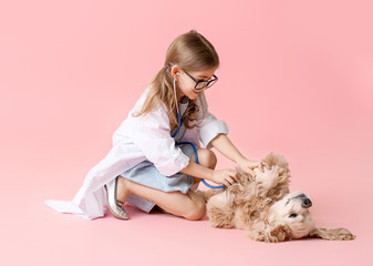 Cute little veterinarian with dog on color background