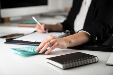 Fototapeta premium Office work. Cropped image of female employee working in office, supplies on tabletop.