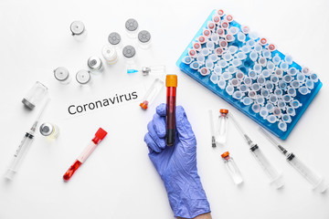 Hand of doctor with blood sample and vaccine for Coronavirus on white background