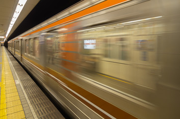 Tokyo subway station platform with motion blurred train