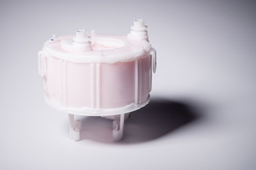 New spare part. Replaceable white plastic inner fuel filter on a gray gradient background