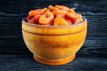 Tasty dried apricots on black wooden background, rusti