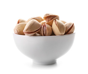 Bowl with tasty pistachio nuts on white background