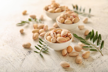 Bowls with tasty pistachio nuts on light background