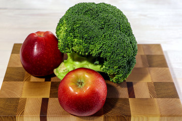 Fresh broccoli and apples on a cutting board. Healthy food. 