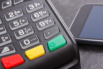 Obraz premium Payment terminal and smartphone with NFC technology using for cashless paying in different places. Finance concept