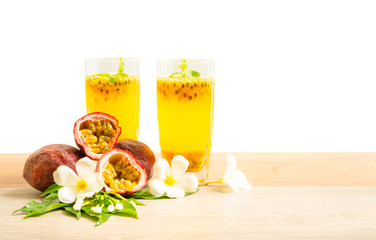 Two glass of passionfruit juice with mint and group of purple skin passionfruit plant, sliced and round fruits on wooden table, isolated on white background, die cut with clipping path image