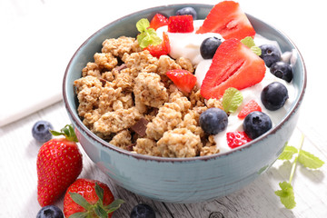 bowl of muesli with cream, blueberry and strawberry