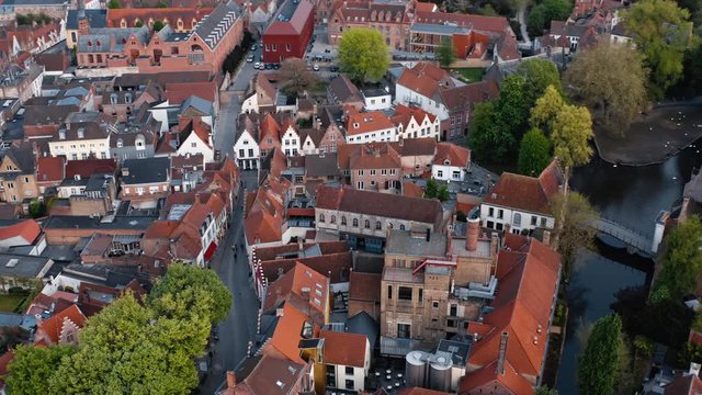 Belgium, Bruges: flight over red roofs of houses in the center of city, river with swans