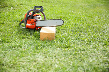 chainsaw on grass close up with copy space. chainsaw on a wooden bar