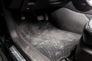 Dirty car floor mats of black rubber with gas pedals and brakes in the workshop for the detailing vehicle before dry cleaning