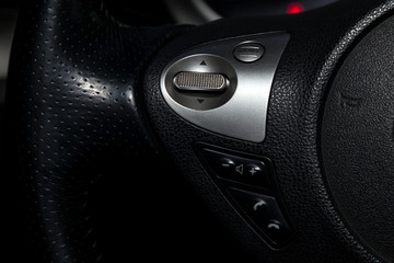 The interior of the car with a view of the multifunction steering wheel, dashboard, and multimedia system audio buttons with light gray trim and hands free system