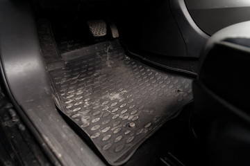Dirty car floor mats of black rubber with gas pedals and brakes in the workshop for the detailing...
