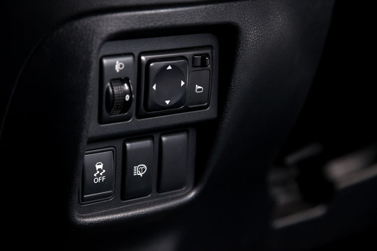 The button for stability control system, side mirrors adjust and headlight washer on black panel of car near the steering wheel to overcome off-road, impassable roads and drive safely in snow or rain