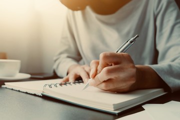 Asian woman is sitting and writing message in personal journal or diary as for remind vent some secret feeling, don't want anyone to know. Is way to cure stress, healing, reduce depression or suicide
