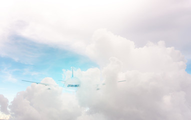 A plane traveling on beautiful white fluffy clouds under vivid and bright blue pastel sky in a suny day