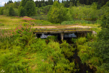 Top view of a country road and the collapsing old bridge over an overgrown river