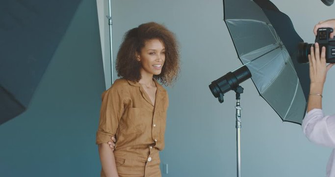 Beautiful african american woman modeling for a fashion photographer, behind the scenes of a professional studio photographer taking photos