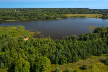 Naklejka na ściany i meble Aerial view from above on a forest lake and and its surroundings