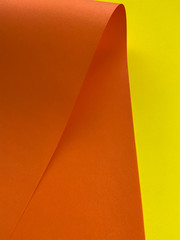 Orange and yellow paper sheets textured background with curve like a wave, close up. Abstract background.